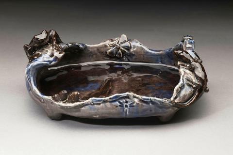 Artwork Rock pool this artwork made of Earthenware, hand modelled with free-form lip and modelled with a frog and lizard at opposite ends, dragonfly and gum leaves. Mulberry glaze with brown details, created in 1921-01-01