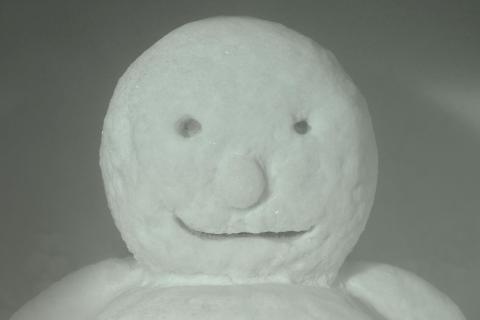 A detail view of an ice sculpture, with a snowman's smiling face.