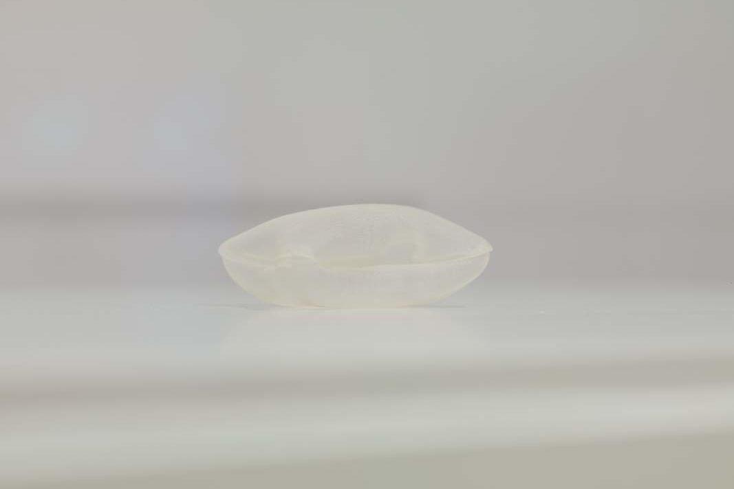 A delicate, tiny sculpture of a white pillow, photographed with a white background.