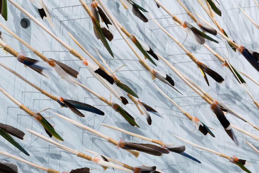 A close-up view of tools made from feathers, which form part of a larger sculptural work.